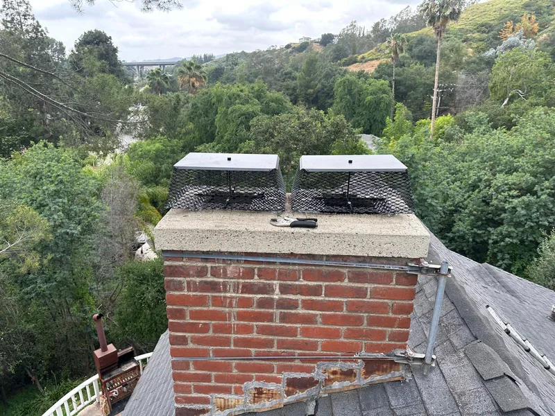 Brick chimney with newly installed stainless caps photographed from the roof for a home sale inspection report
