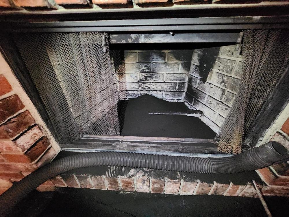 Heavy glazed creosote coating the smoke chamber and damper of a masonry chimney before cleaning